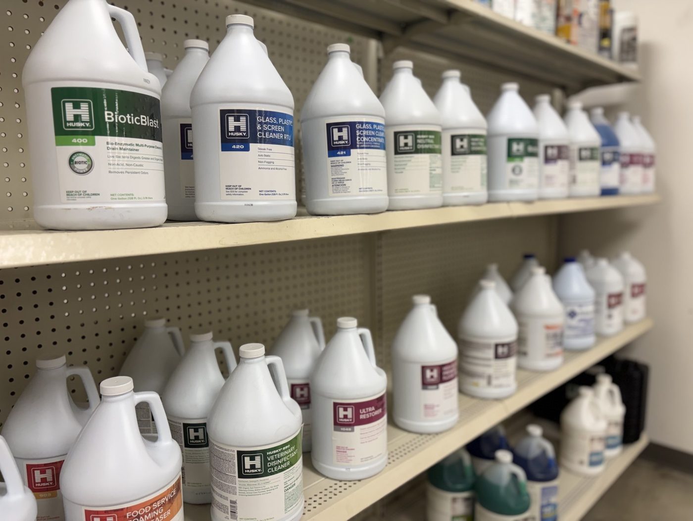 Shelves of commercial cleaning chemicals and concentrates on the janitorial side of the counter